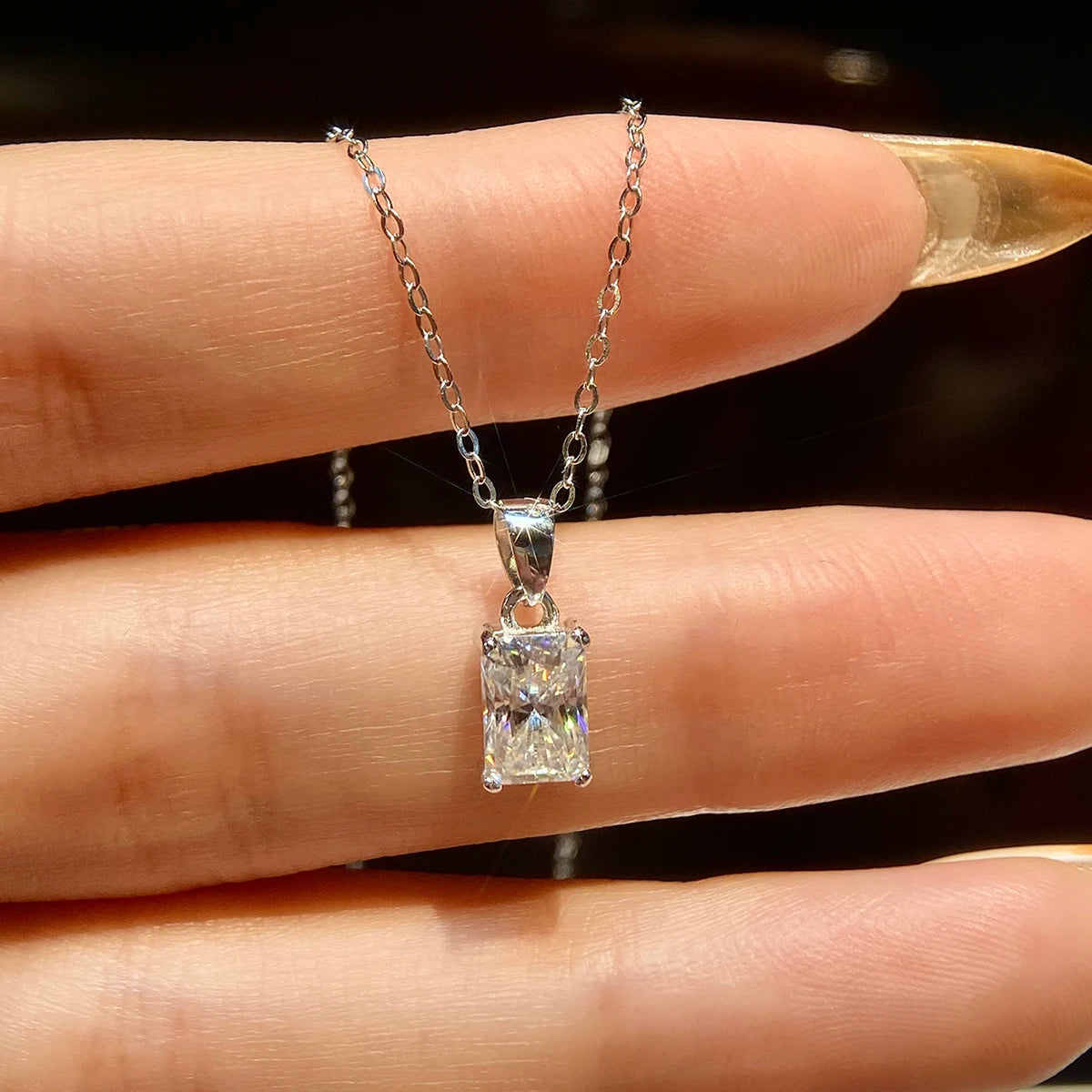 Radiance Rectangular Moissanite Pendant in 18K White Gold-Plated setting, held delicately in a hand.
